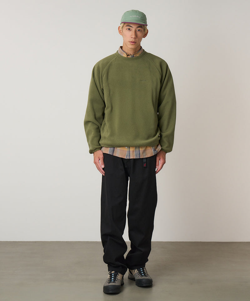 Person wearing a Gramicci green sweatshirt, plaid shirt, black Gramicci Pants, and green cap against a plain background