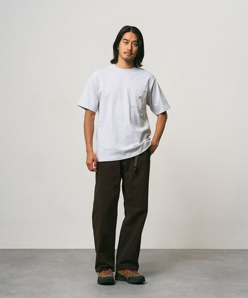 Model wearing a ash heather Gramicci One Point Tee and brown pants on a light-tone background.