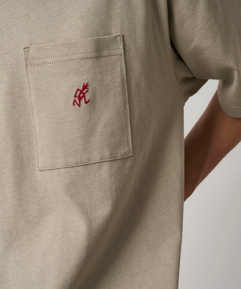 Model wearing a Gramicci beige One Point Tee with a small running man graphic against a light-tone background.