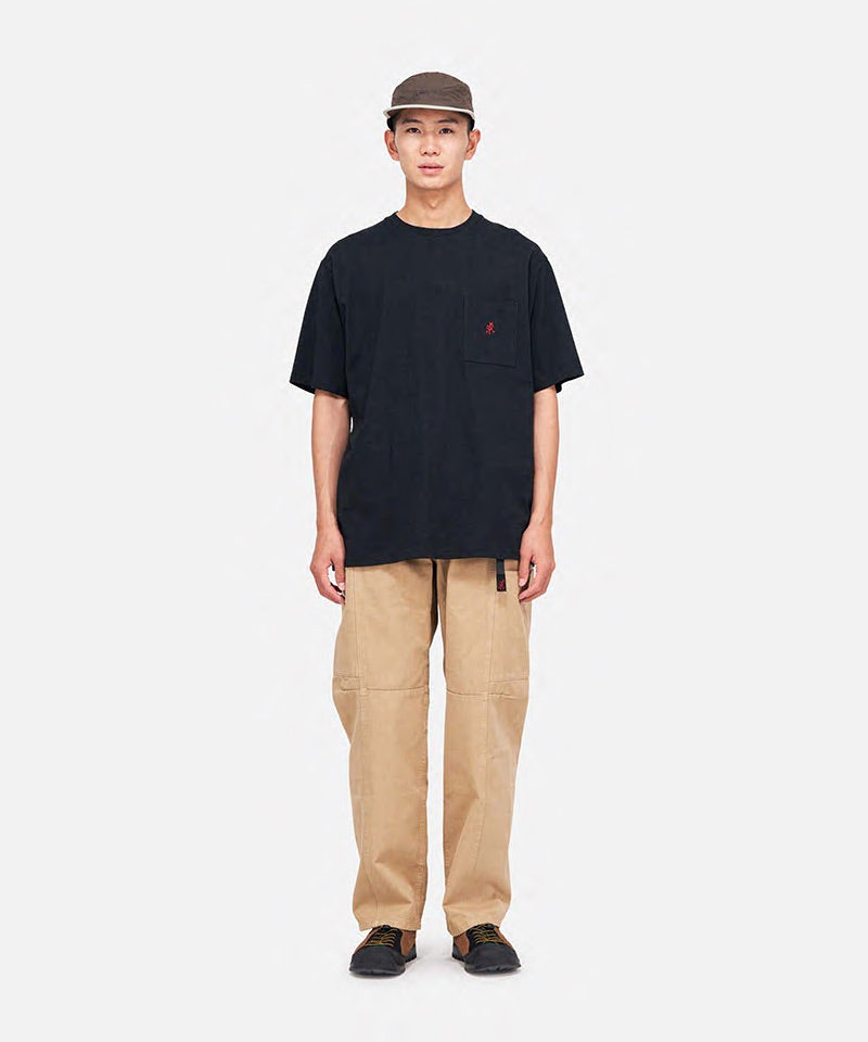 Model wearing a vintage black Gramicci One Point Tee with a small running man graphic and khaki pants on a light-tone background.