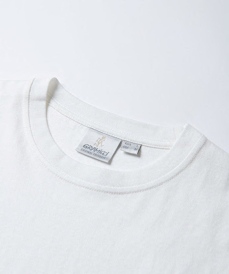 Close-up of a white Gramicci One Point Tee neck on a light-tone background.