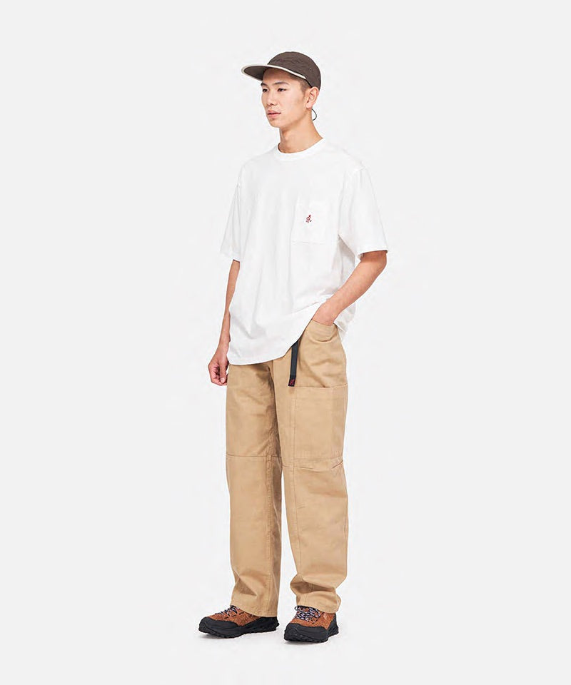 Model wearing a white Gramicci One Point Tee with a small running man graphic and khaki pants on a light-tone background.