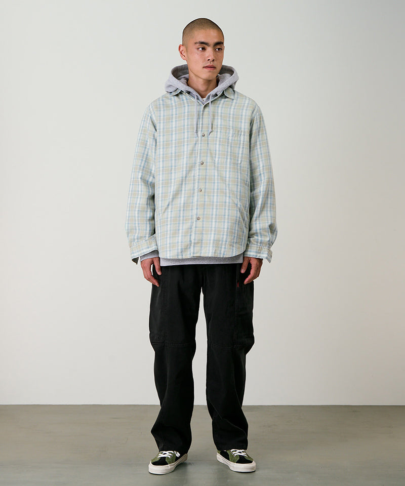 Model wearing black Gramicci Voyager Pants and a plaid jacket on a light-tone background.