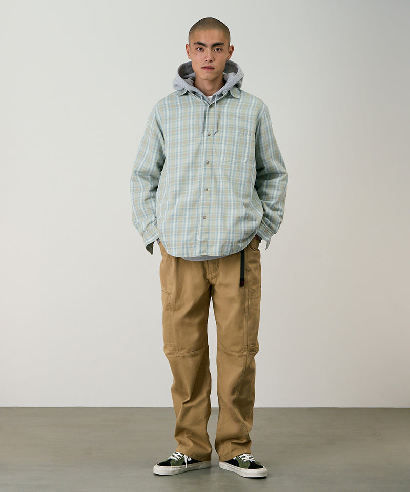 Model wearing chino colored Gramicci Voyager Pants and a plaid jacket on a light-tone background.