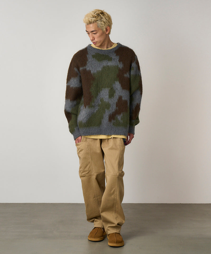 Model wearing chino colored Gramicci Voyager Pants and a mohair sweater on a light-tone background.