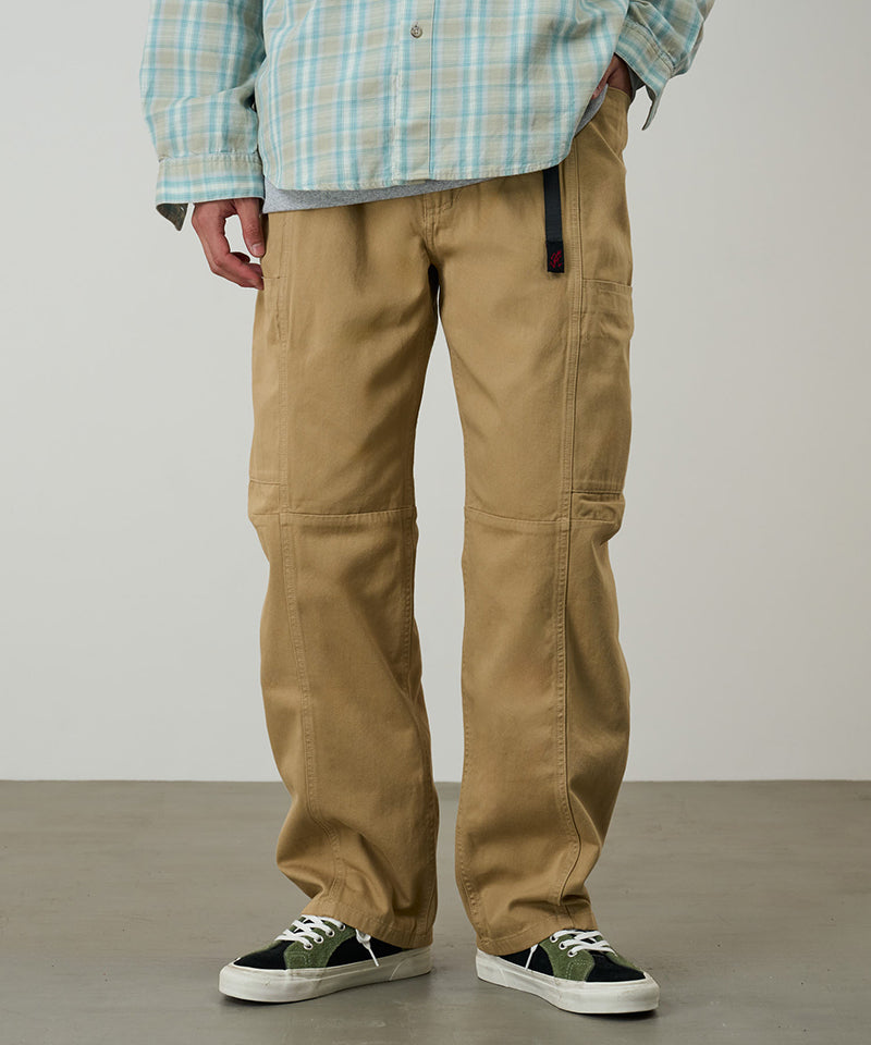 Model wearing chino colored Gramicci Voyager Pants and a plaid jacket on a light-tone background.