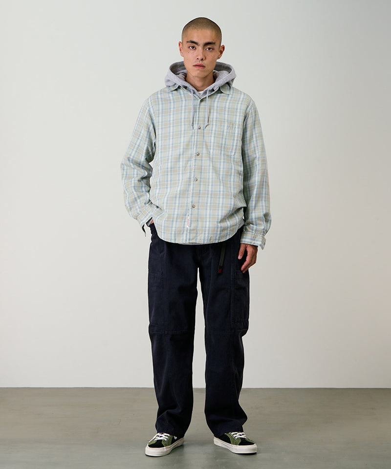 Model wearing double navy Gramicci Voyager Pants and a plaid jacket on a light-tone background.