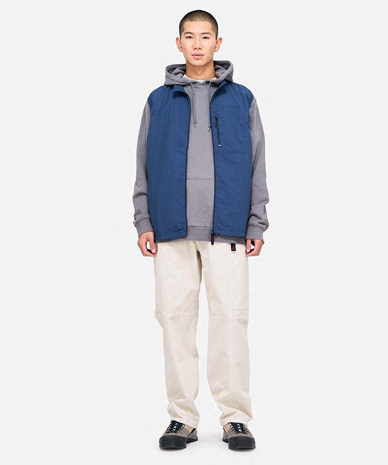 Model wearing greige colored Gramicci Voyager Pants and a blue jacket on a light-tone background.