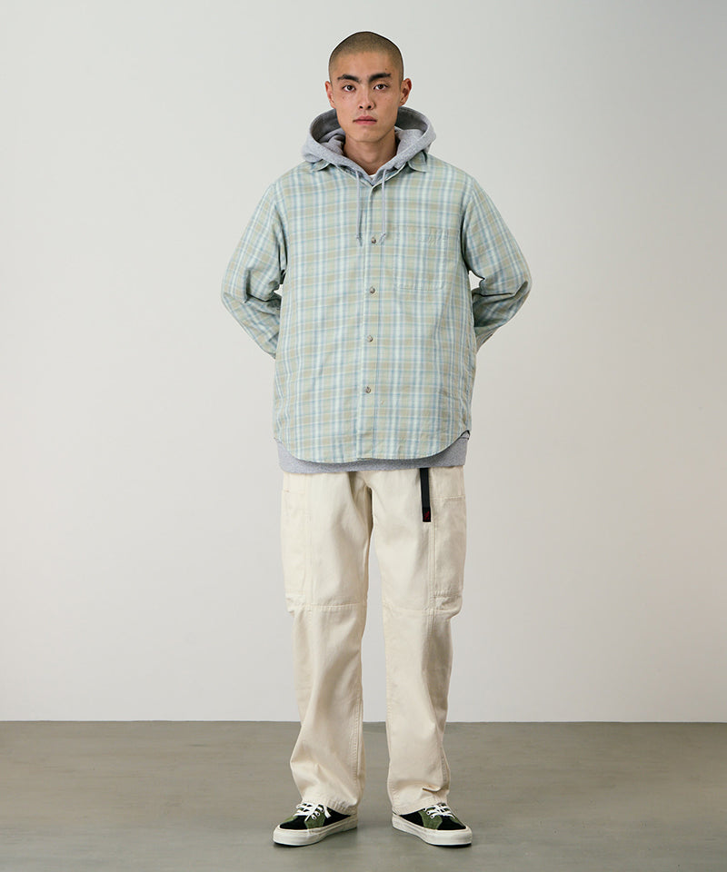 Model wearing greige colored Gramicci Voyager Pants and a plaid jacket on a light-tone background.