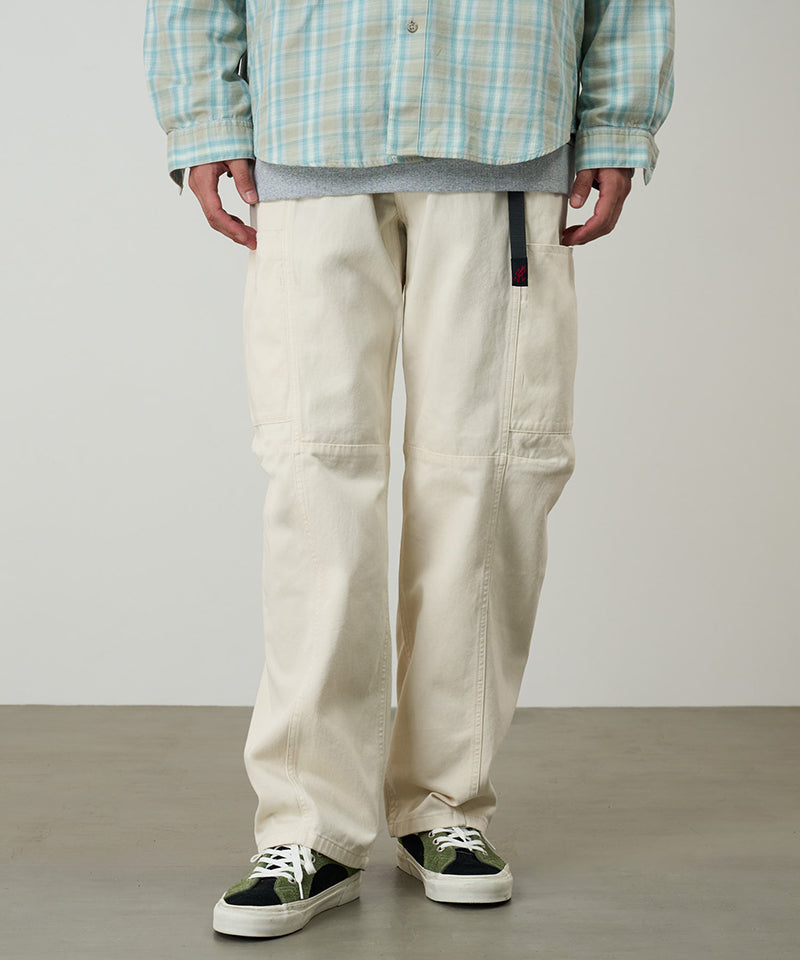Model wearing greige colored Gramicci Voyager Pants and a plaid jacket on a light-tone background.