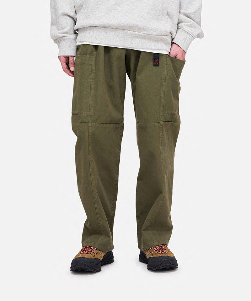 Model wearing olive Gramicci Voyager Pants and a heather hoodie on a light-tone background.