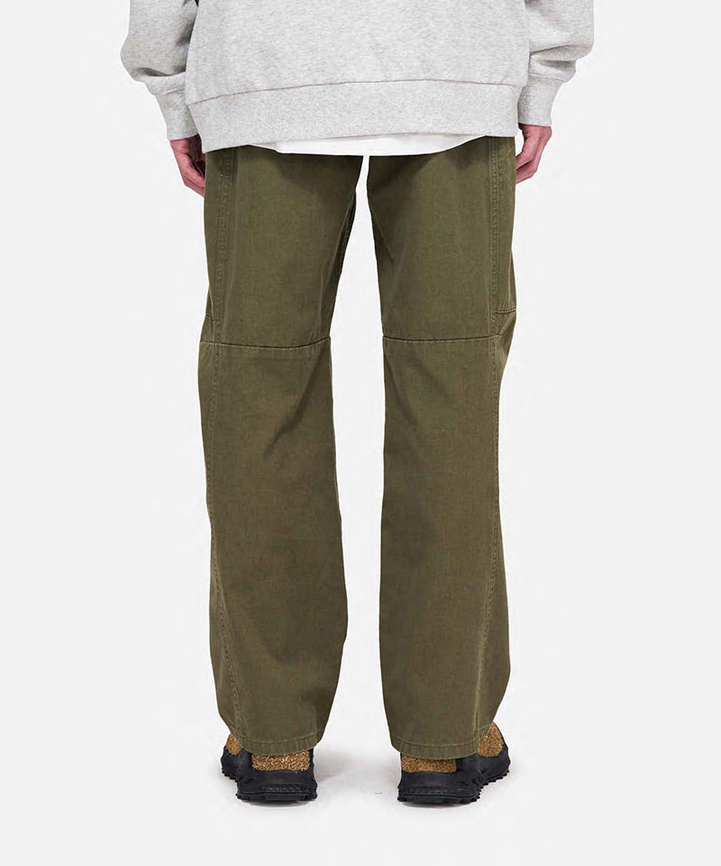 Back view of a model wearing olive Gramicci Voyager Pants and a heather hoodie on a light-tone background.
