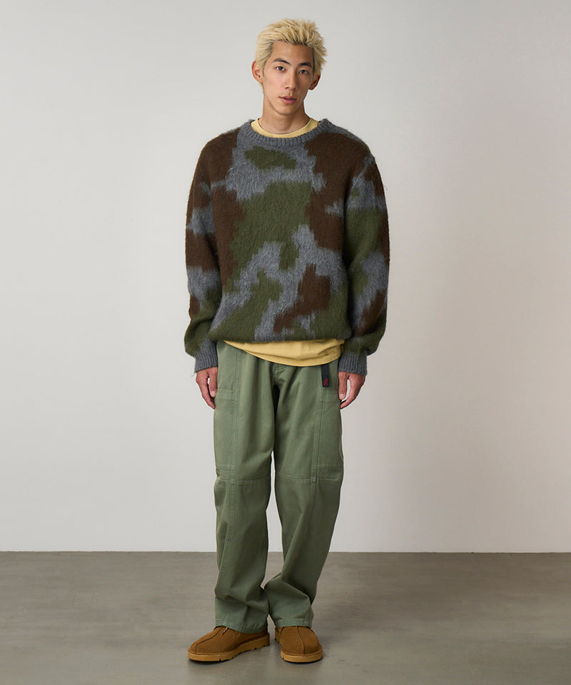 Model wearing sage colored Gramicci Voyager Pants and a mohair sweater on a light-tone background.