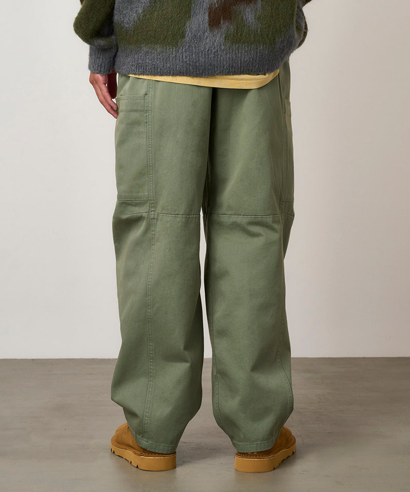Back view of a model wearing sage colored Gramicci Voyager Pants and a mohair sweater on a light-tone background.