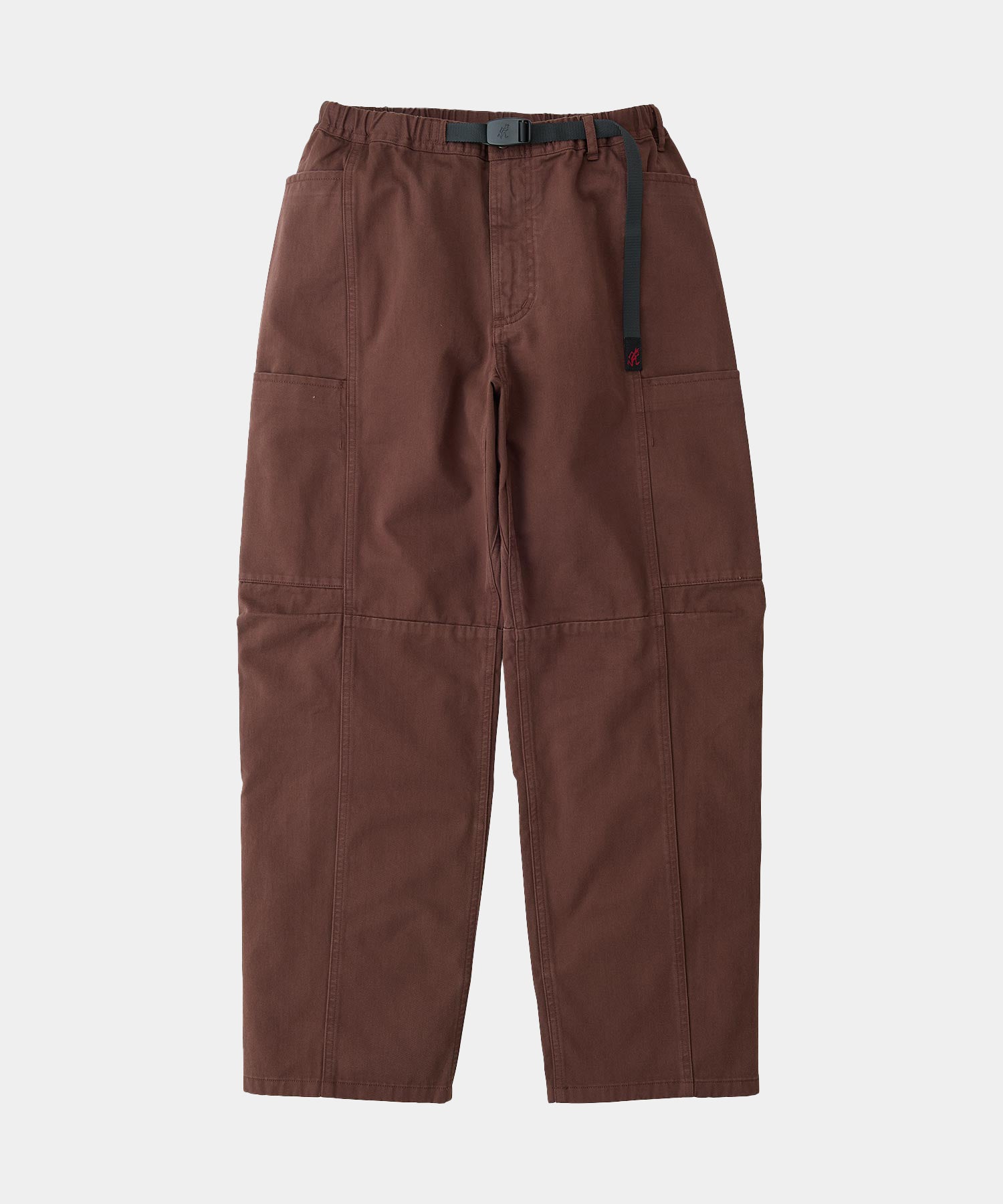 Tobacco colored Gramicci Voyager Pants with a belt against a light-tone background.