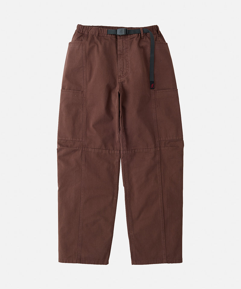 Tobacco colored Gramicci Voyager Pants with a belt against a light-tone background.