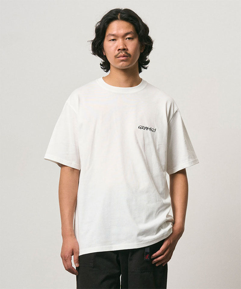 Model wearing a Gramicci white Bass Tee against a light-tone background.