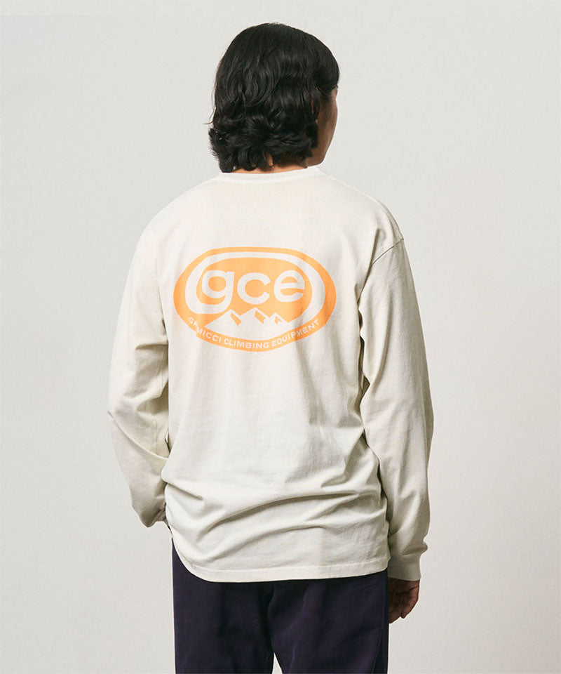 Back view of a model wearing a Gramicci natural pigment colored GCE Tee Pigment Dyed with a graphic against a light-tone background.