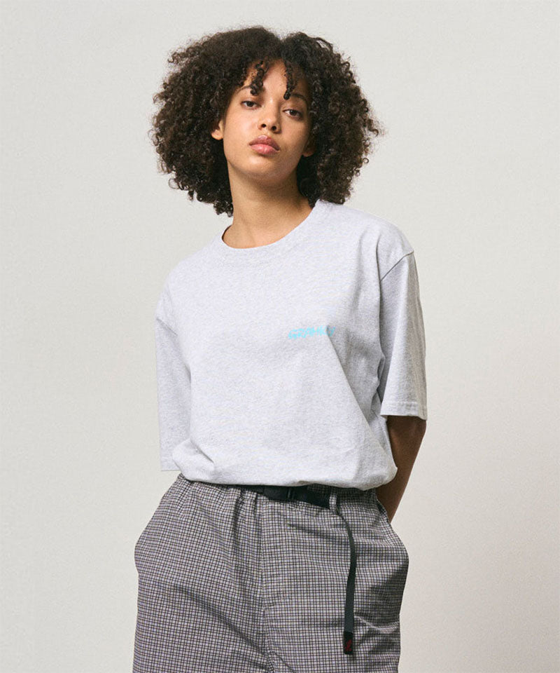 Model wearing a Gramicci ash heather color Joker Tee against a light-tone background.