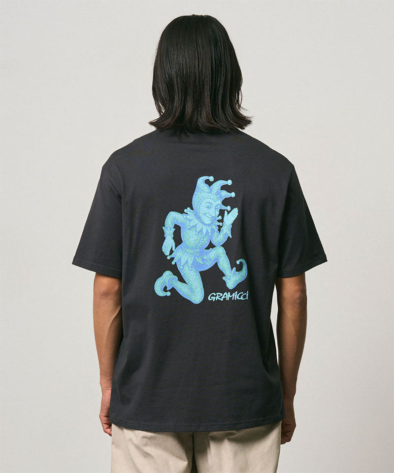 Back view of a model wearing a Gramicci vintage black Joker Tee with a teal graphic against a light-tone background.
