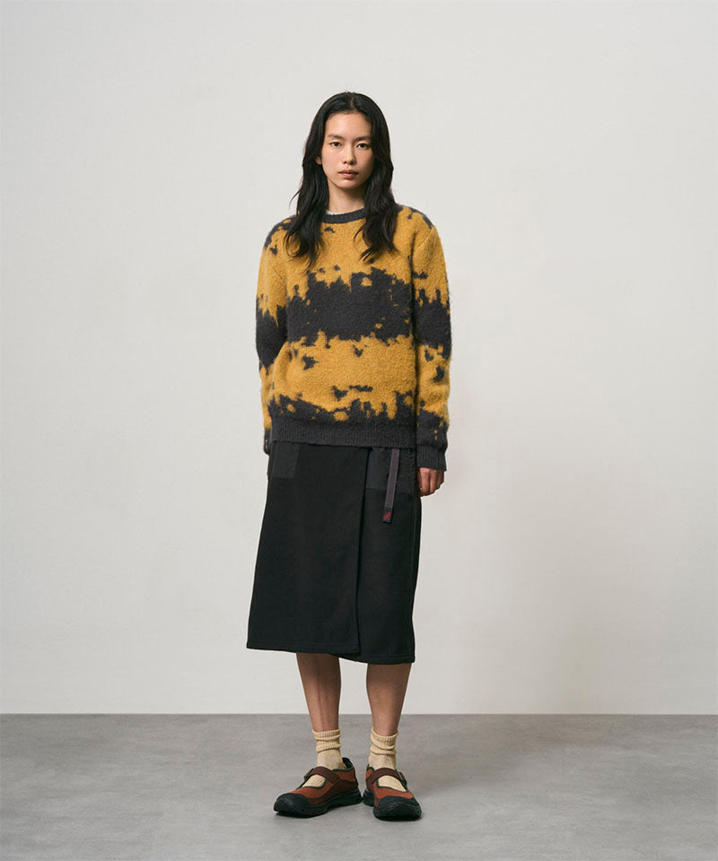 Model wearing a black Gramicci Thermal Fleece Skirt and a orange and black sweater on a light-tone background.