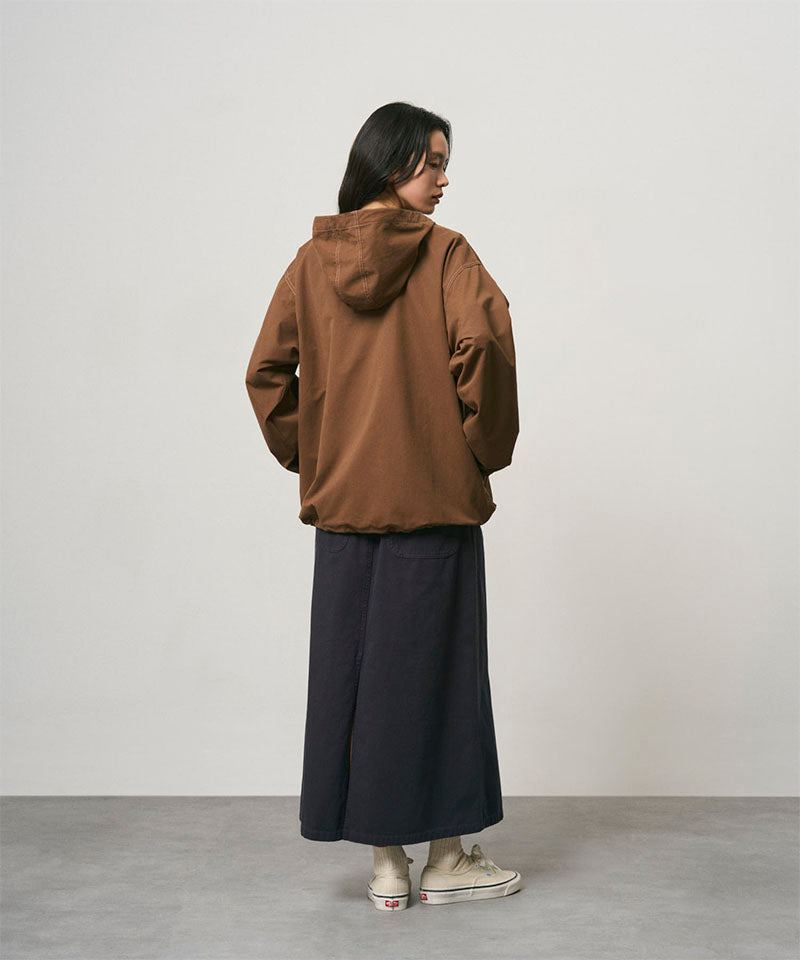 Back view of a model wearing a double navy Gramicci 5-Pocket Skirt and a brown jacket on a light-tone background.