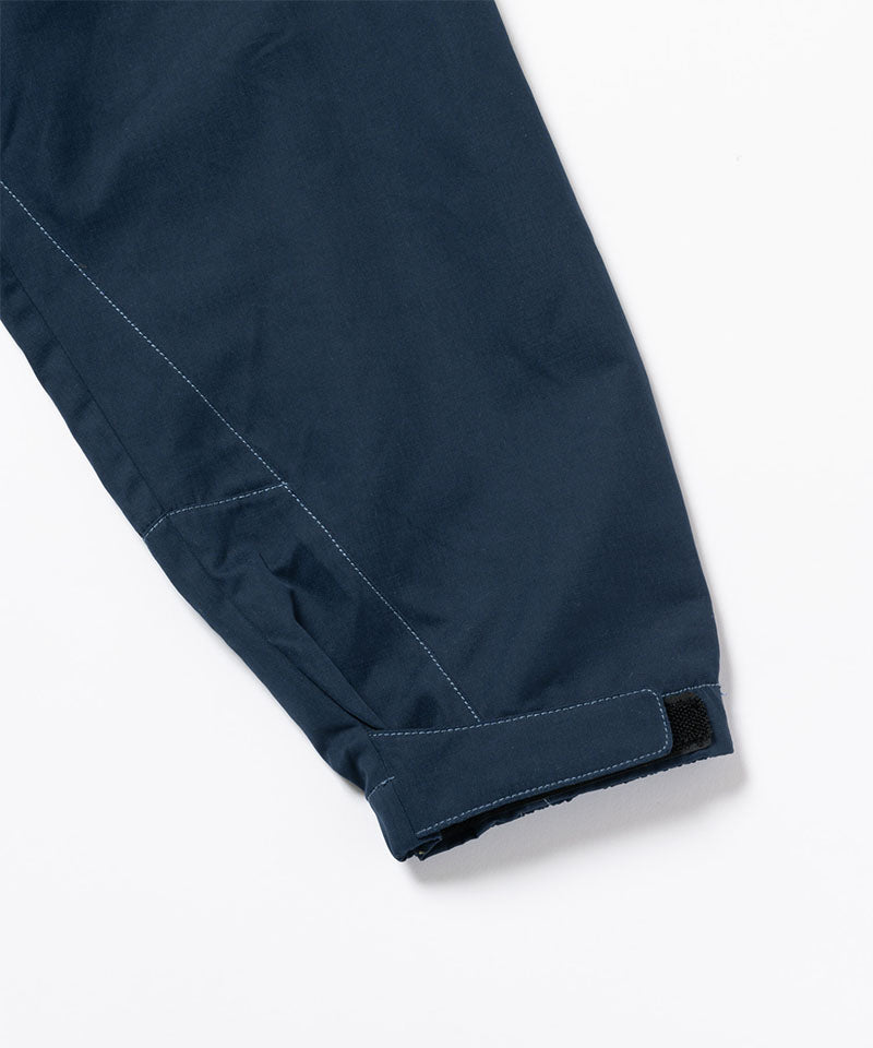 Close-up of a dark navy Gramicci Milton Hooded Jacket sleeve on a light-tone background.