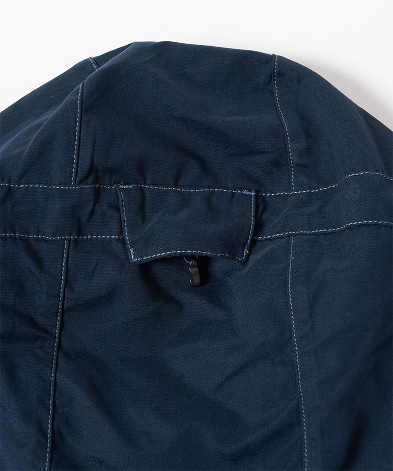 Close-up of a dark navy Gramicci Milton Hooded Jacket on a light-tone background.