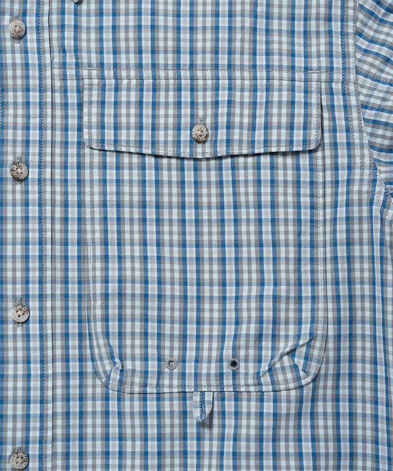 Close-up view of a Gramicci Poplin Millwood Shirt pocket in blue plaid on a light-tone background.