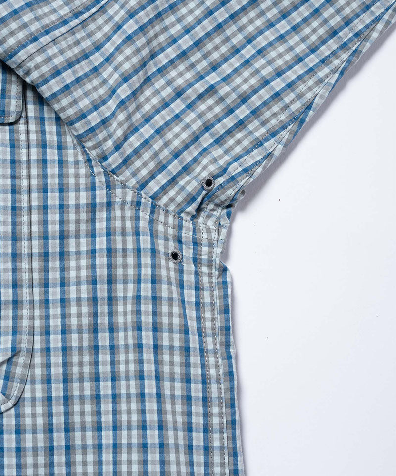 Close-up view of a Gramicci Poplin Millwood Shirt pocket in blue plaid on a light-tone background.