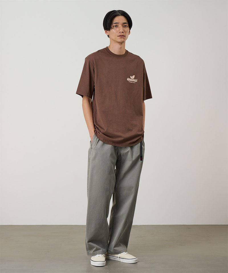 Model wearing a Natural Dyed Gramicci Pant Straight Fit in the color olive and brown shirt on a light-tone background.