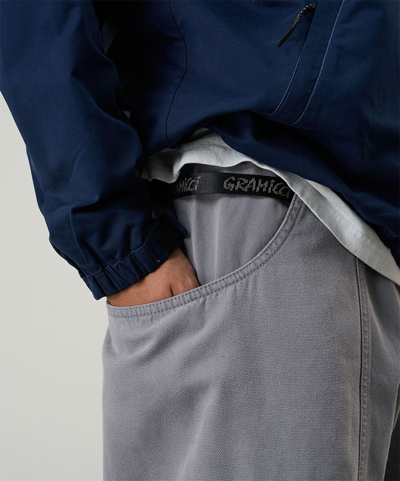 Model wearing a Gramicci natural dyed grey Gadget Pants with visible branding against a light-tone background.