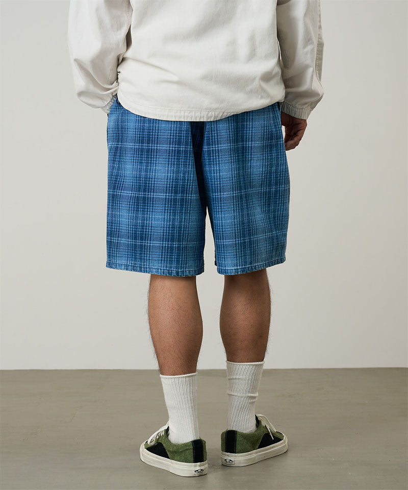 Back view of a model wearing a Gramicci indego Lagoon Short Denim Plaid against a light-tone background.