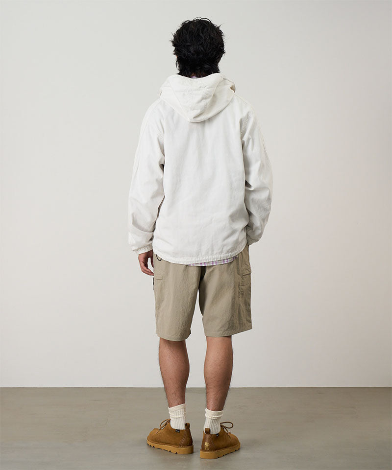 Back view of a model wearing milk tea colored Gramicci Nylon Cliff Short and a white jacket on a light-tone background.