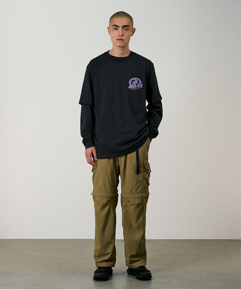 Model wearing khaki Gramicci Convertible Cargo Pants and a black shirt on a light-tone background.