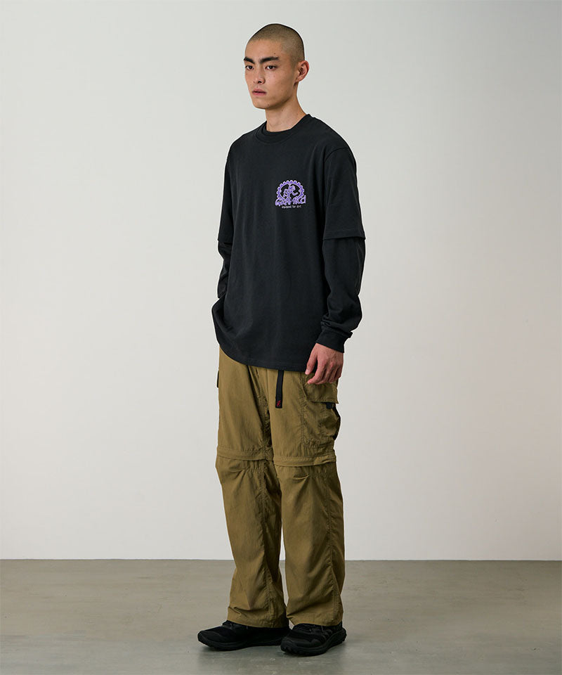 Model wearing khaki Gramicci Convertible Cargo Pants and a black shirt on a light-tone background.