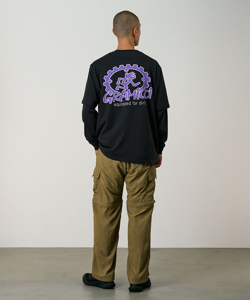 Back view of a model wearing khaki Gramicci Convertible Cargo Pants and a black shirt on a light-tone background.