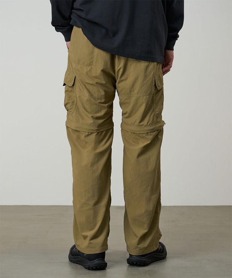 Back view of a model wearing khaki Gramicci Convertible Cargo Pants and a black shirt on a light-tone background.