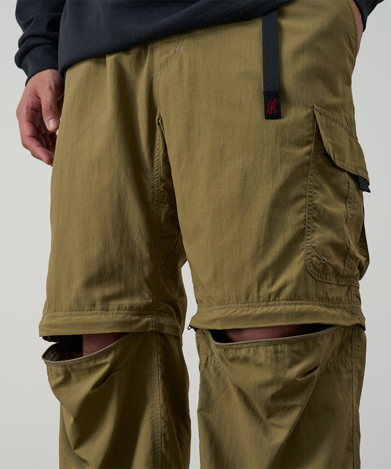 Model wearing khaki Gramicci Convertible Cargo Pants and a black shirt on a light-tone background.