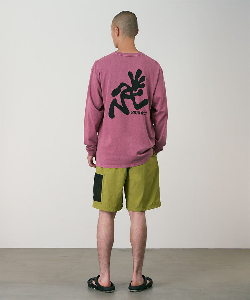 Back view of a model wearing field green Gramicci Guide Shorts and a red shirt on a light-tone background.