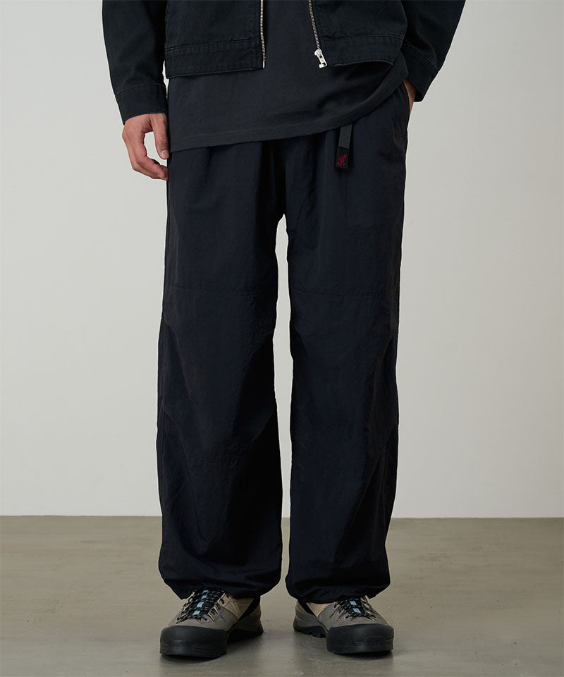Model wearing black Gramicci Nylon Paneled Trek Pants and a black jacket on a light-tone background.
