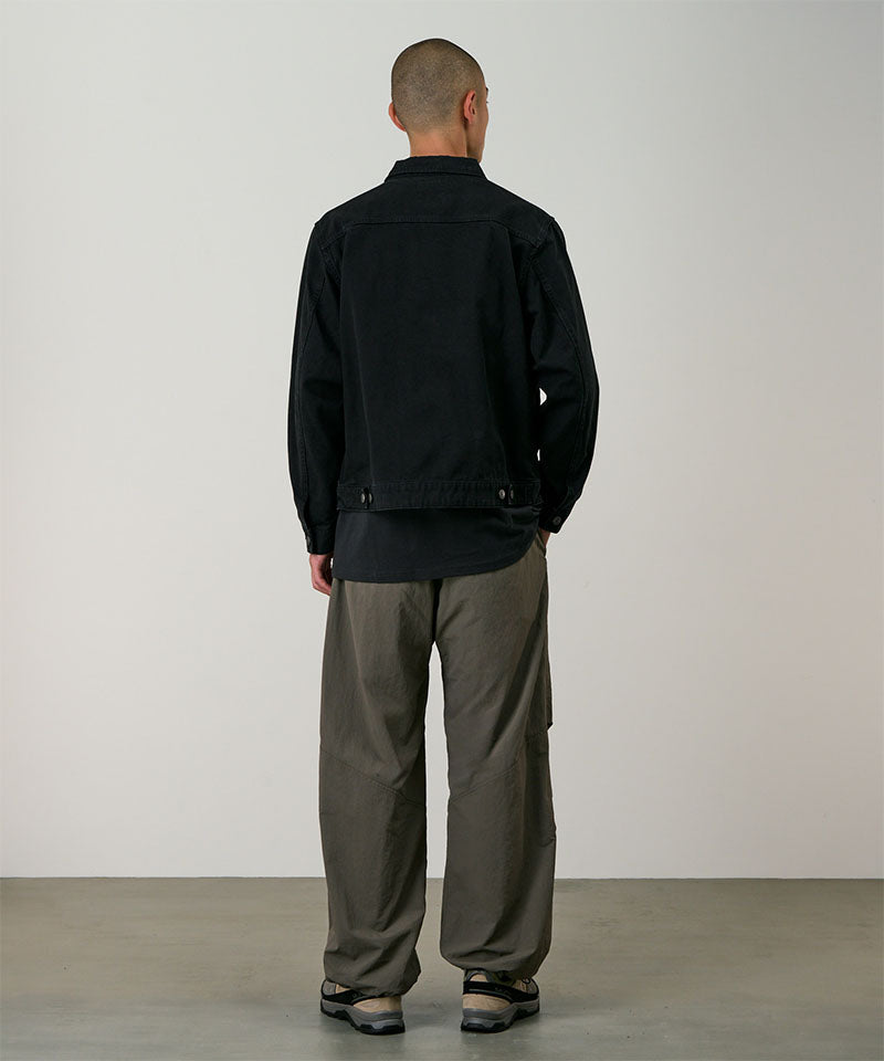 Back view of a model wearing granite colored Gramicci Nylon Paneled Trek Pants and a black jacket on a light-tone background.