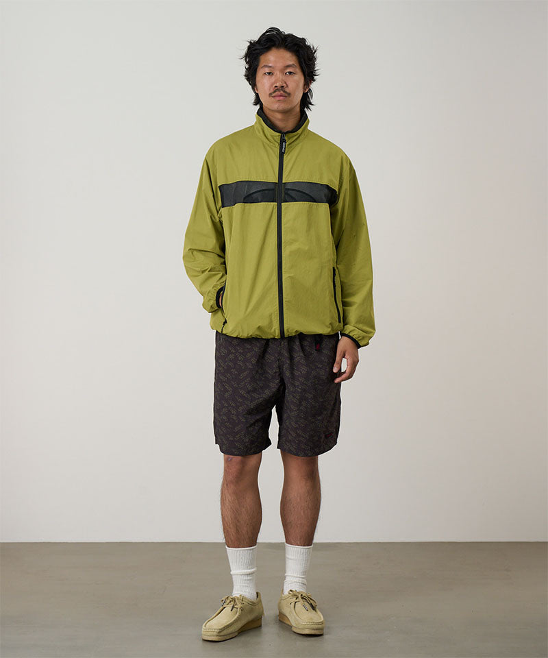 Model wearing brown leaf colored Gramicci Nylon Packable G-Short and a olive jacket on a light-tone background.