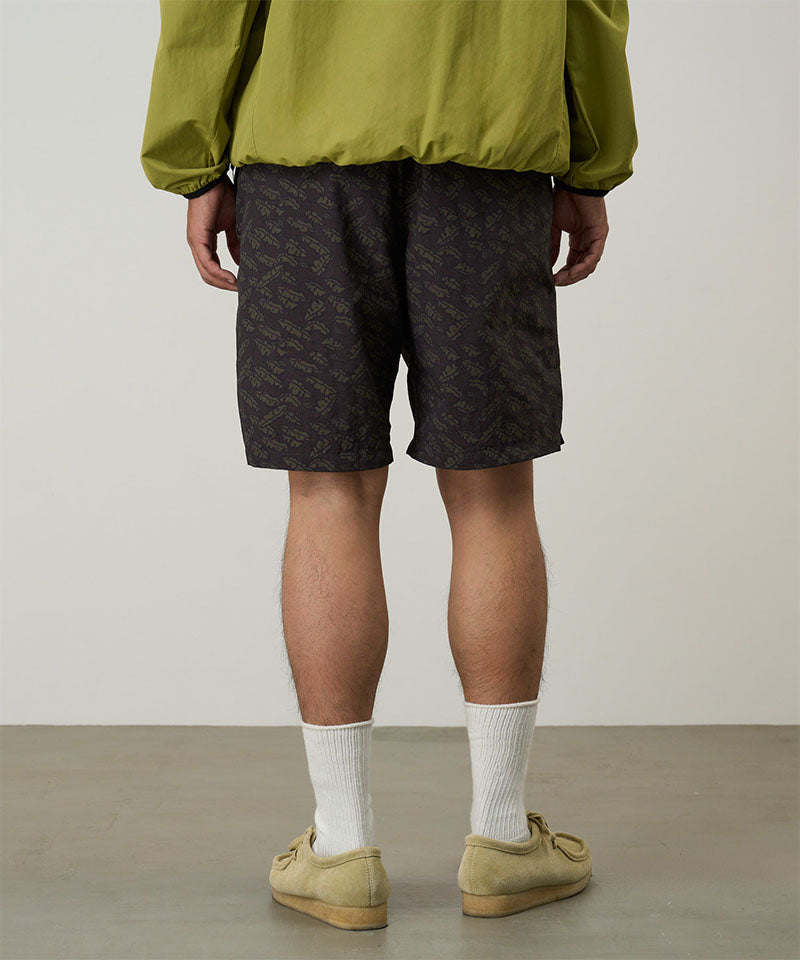 Back view of a model wearing brown leaf colored Gramicci Nylon Packable G-Short and a olive jacket on a light-tone background.