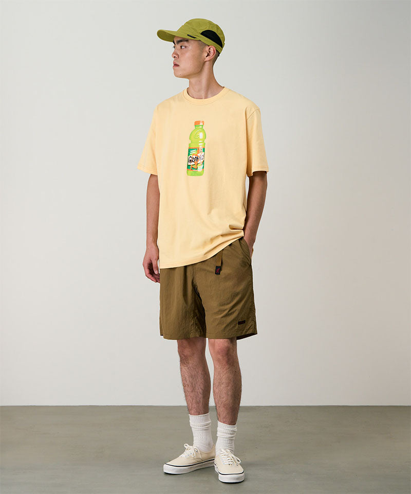 Model wearing coyote colored Gramicci Nylon Packable G-Shorts and a mango colored shirt on a light-tone background.