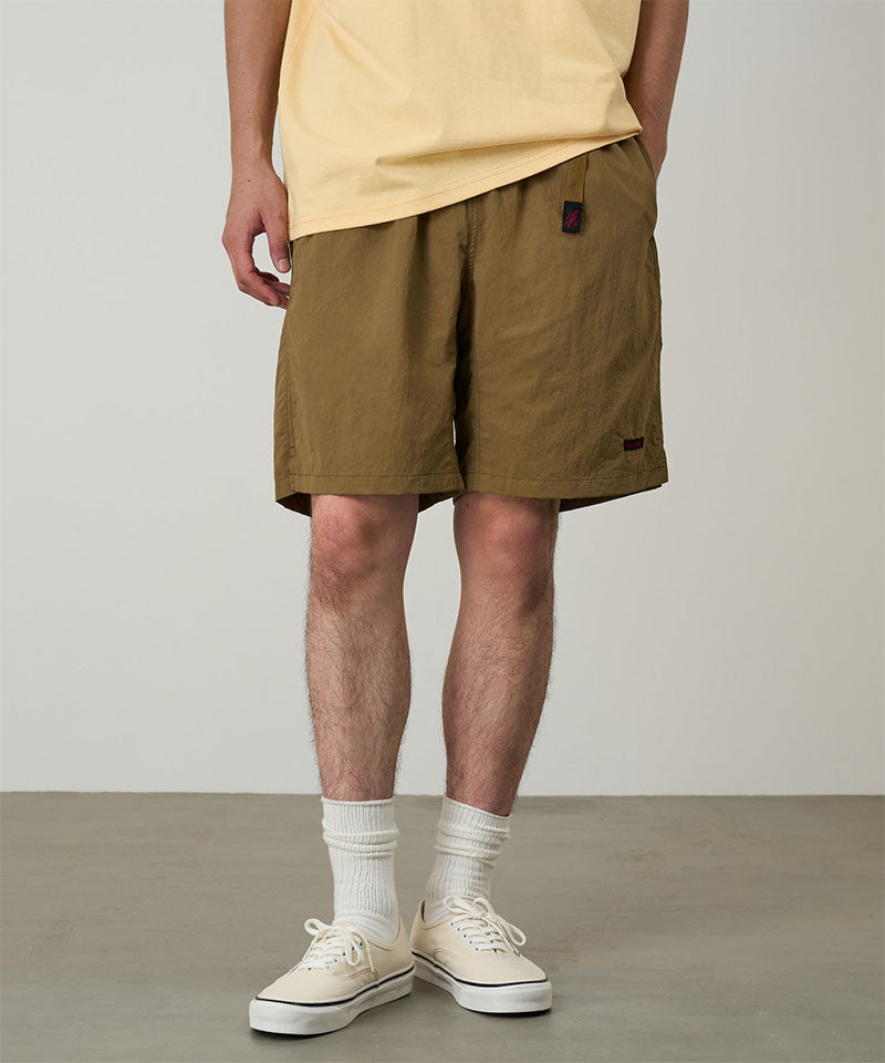 Model wearing coyote colored Gramicci Nylon Packable G-Shorts and a mango colored shirt on a light-tone background.