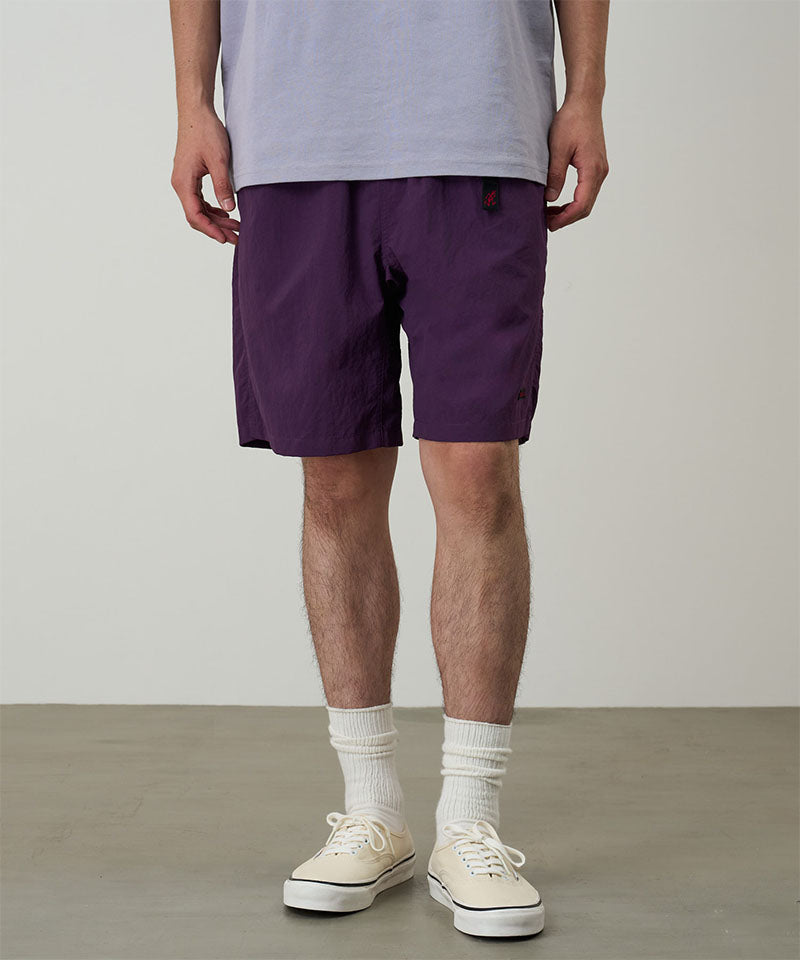 Model wearing deep purple Gramicci Nylon Packable G-Shorts and a lavender shirt on a light-tone background.