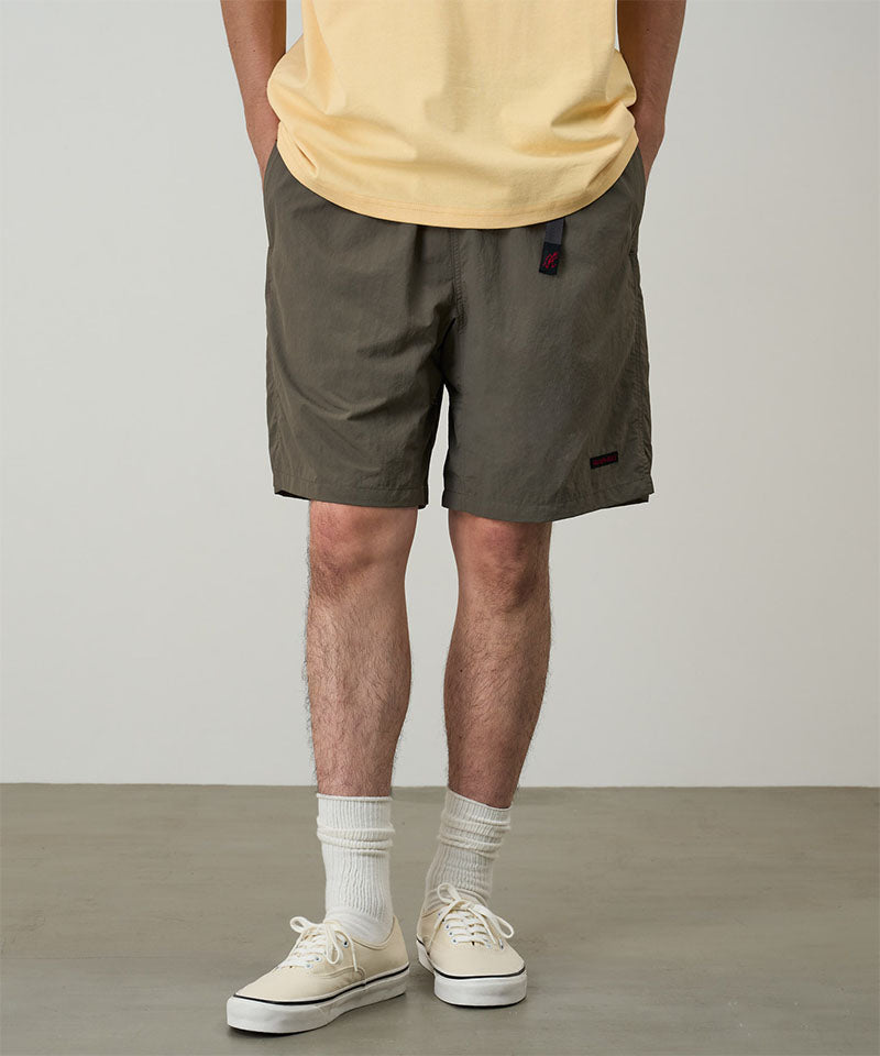 Model wearing granite colored Gramicci Nylon Packable G-Shorts and a mango colored shirt on a light-tone background.
