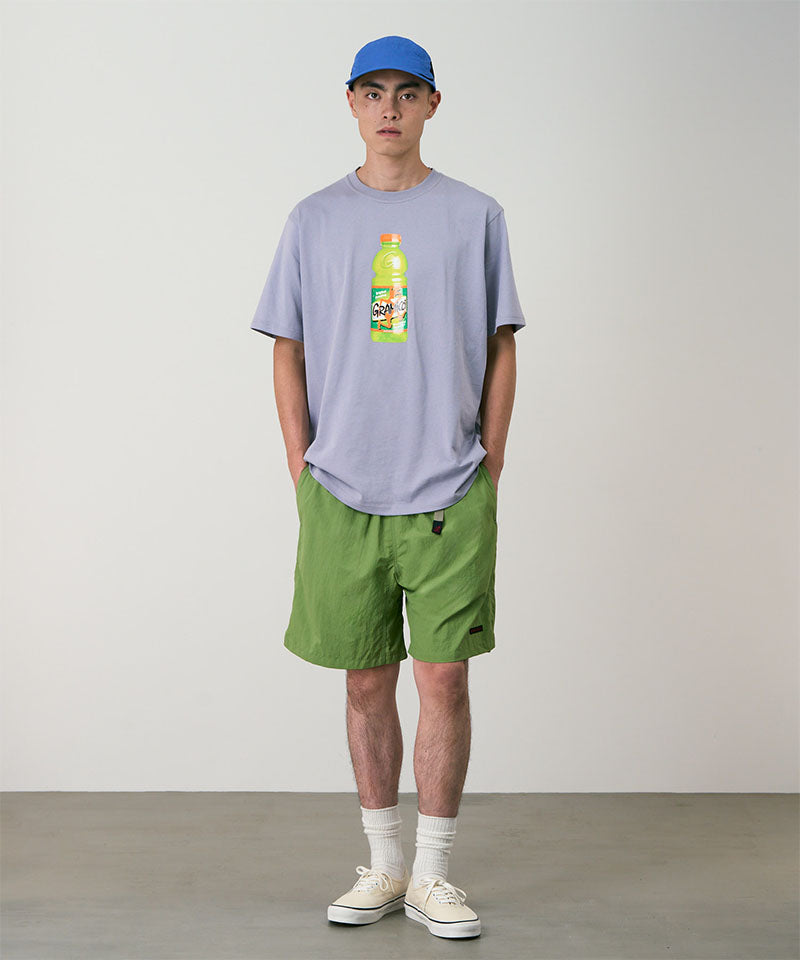 Model wearing jade green Gramicci Nylon Packable G-Shorts and a lavender shirt on a light-tone background.