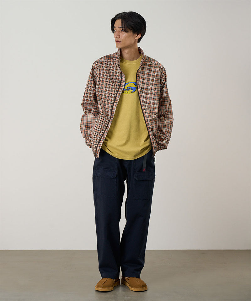 Model wearing double navy Gramicci EQT Pant and a plaid jacket on a light-tone background.
